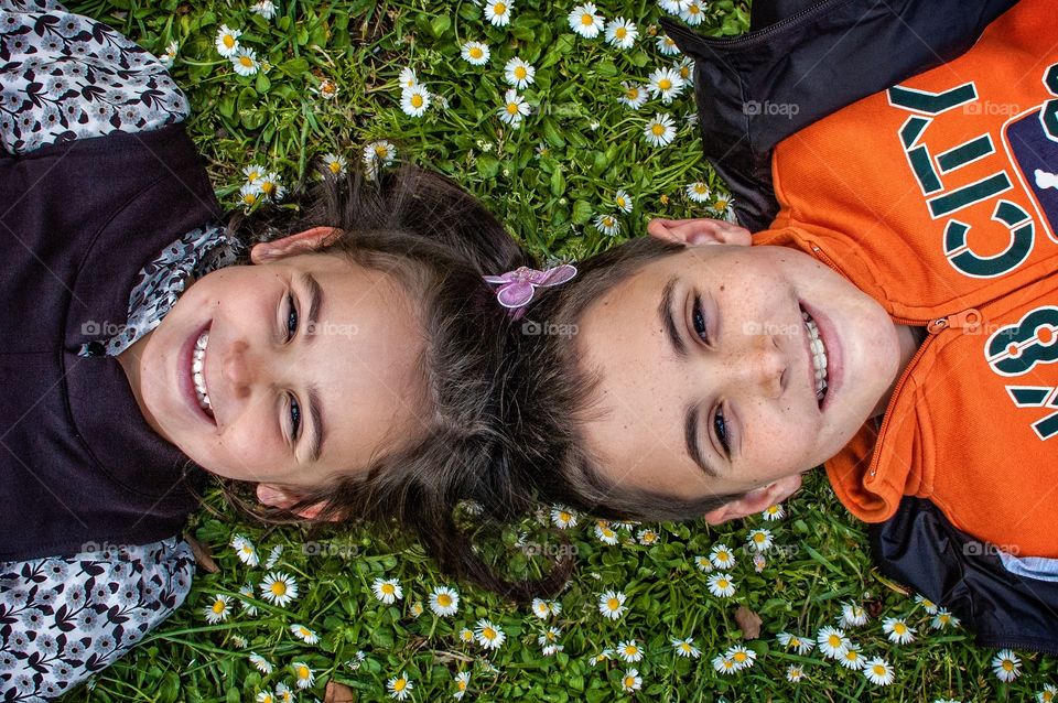 Laughing children lying in a field of daisies