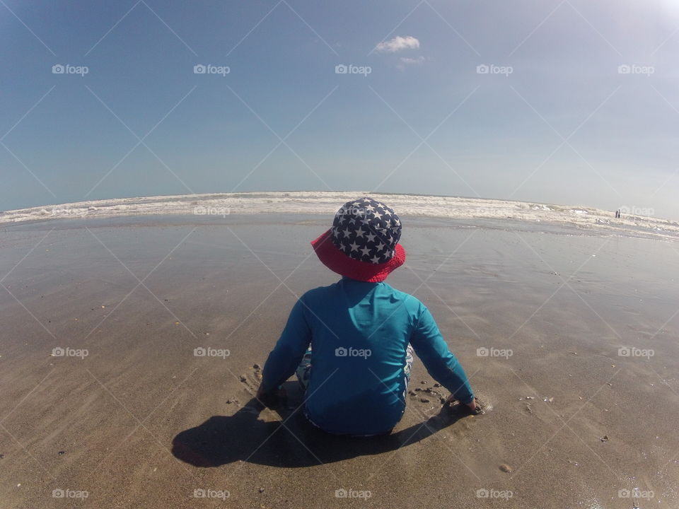 Child sitting on the beach watching the ocean