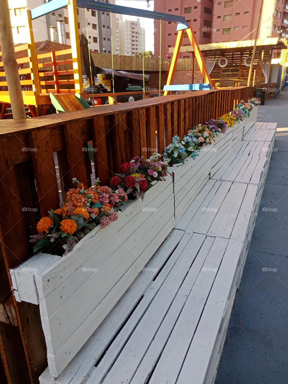 Flowers on benches made of crates. Waiting place in front of a restaurant
