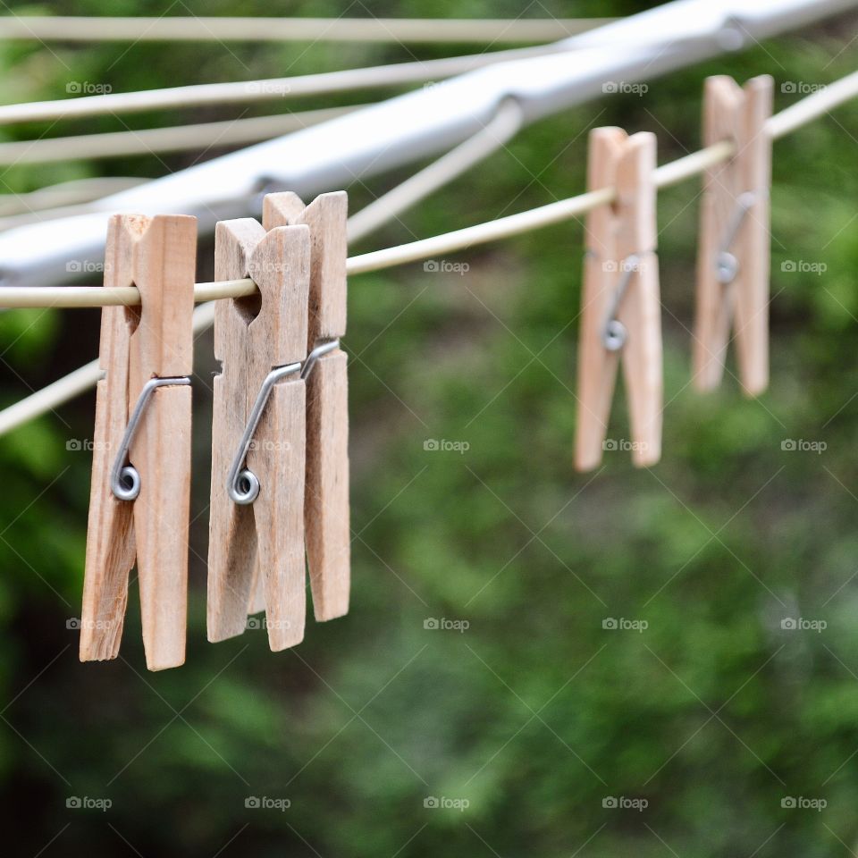 Five wooden clothes pegs on a washing line in a garden