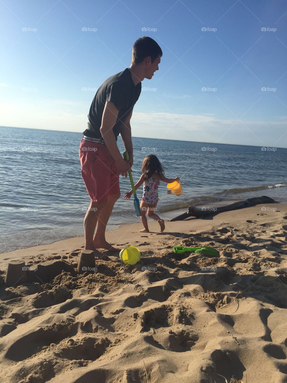 Fun in the sun. Dad and daughter on the beach playing in the sand. 