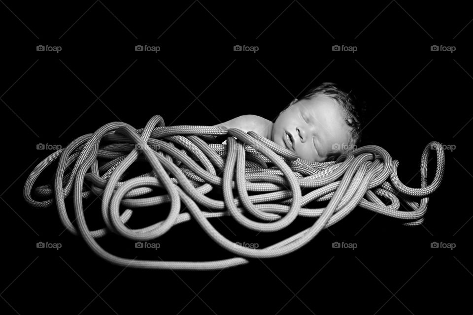 Newborn baby lying on tangled rope