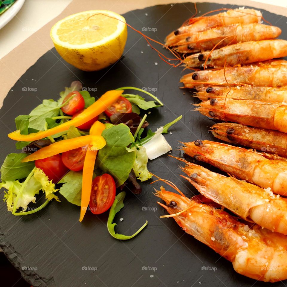 yummy scampis with salad,  nicely arranged on a black wooden board