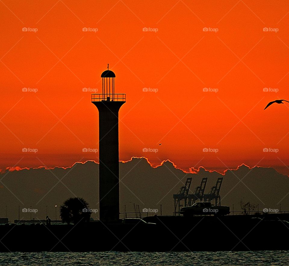 Sunrise, sunset, and the moon - The silhouetted tower reaches high in the sky under the guise of the tangerine sunset