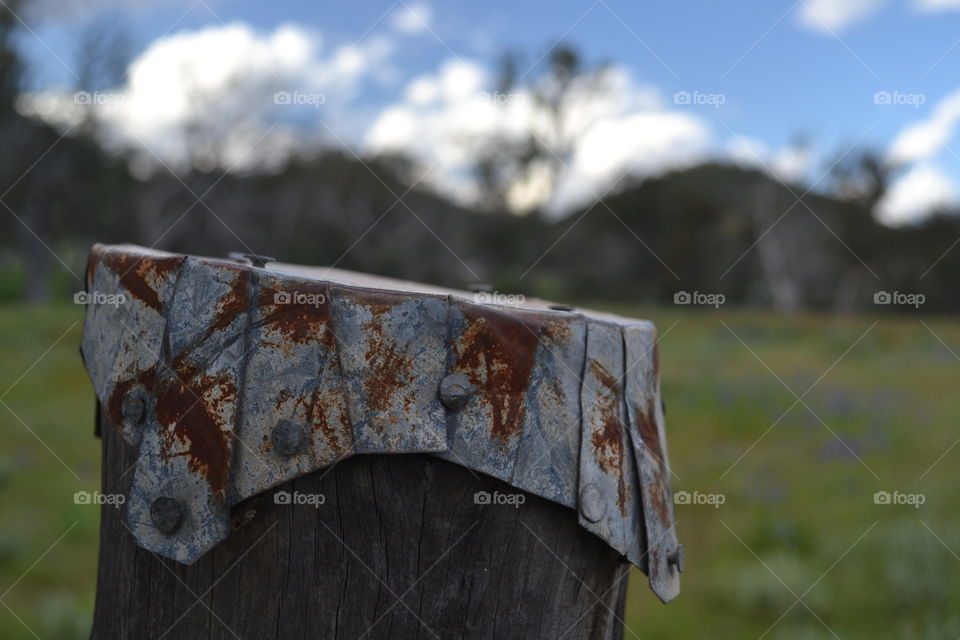 Folded rusted galvanised metal over fence post