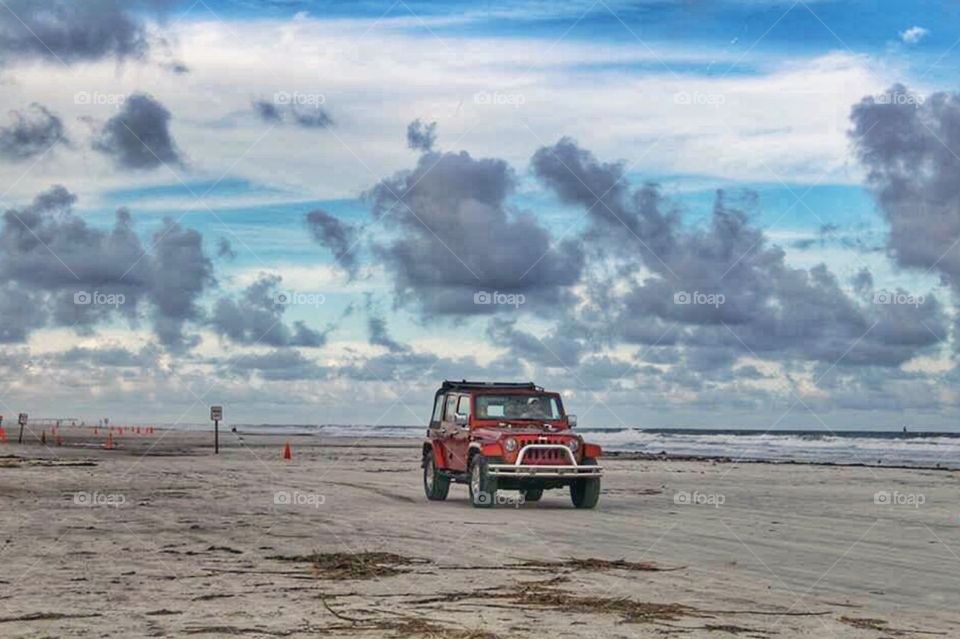 Beach drive. A red jeep driving on the beach