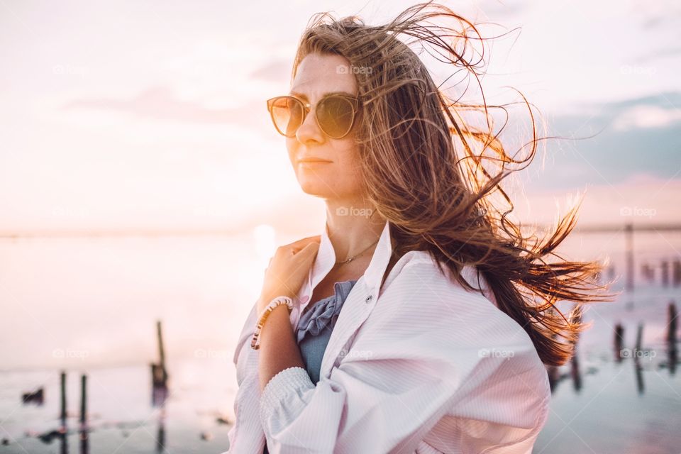 Beautiful woman with hair blowing in the wind looking away at the sunset