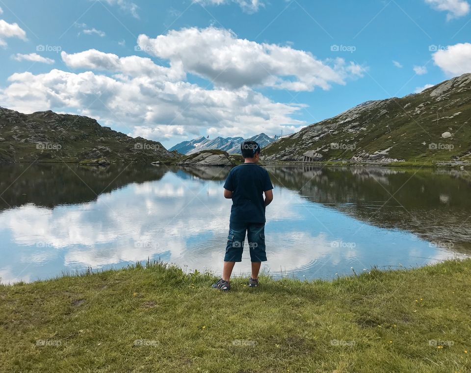 The boy standing at the lake shore in the mountain