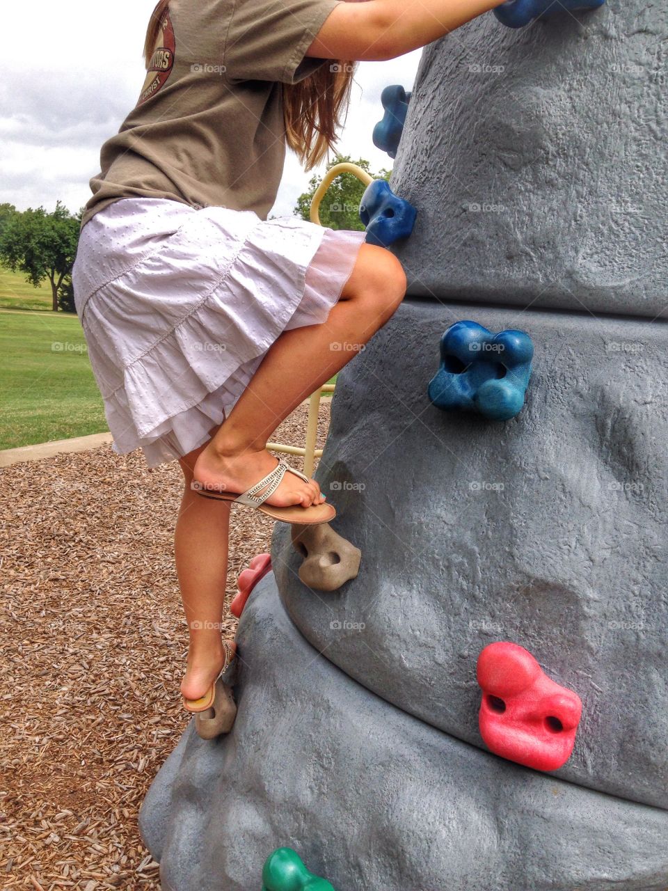 Ready for Everest. Girl climbing rock wall at the park