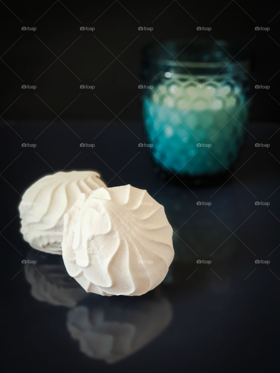 Tasty sweet snack. Still life with marshmallows and a beautiful glass of milk on a dark background, on a glossy surface with reflection