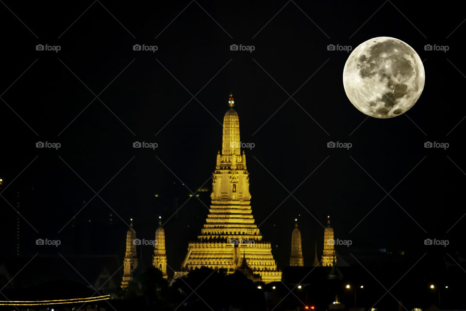 The beauty of the full Moon and Wat Arun at night with gold , The oldest temple of the Chao Phraya River in Bangkok Thailand.