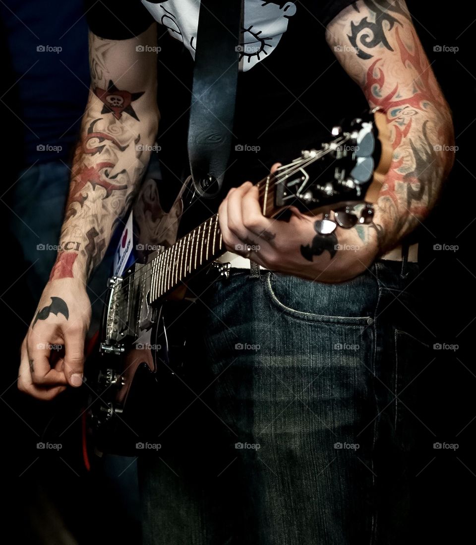 Man with tattooed arms plays guitar