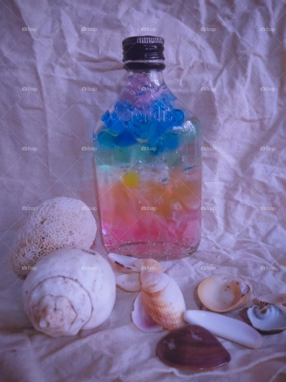 This is a creative and a colourful idea.There is a bottle with a full of colourful marbles and there can be seen some sea shells near the bottle . Most of sea shells are in white colour. however this is very creative and colourful idea..❇️