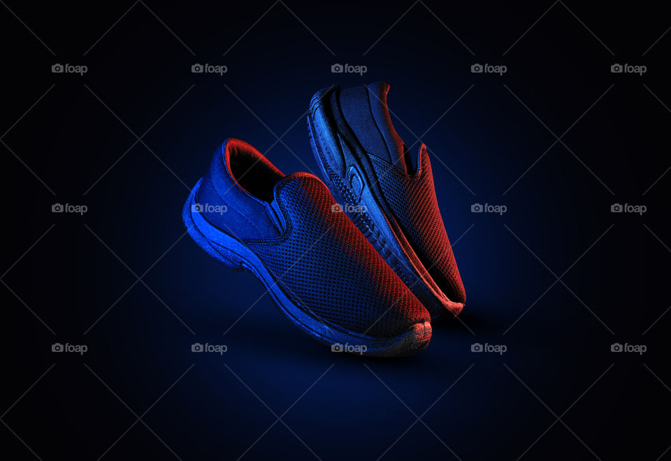 A pair of shoes with dramatic lighting in red and blue color
