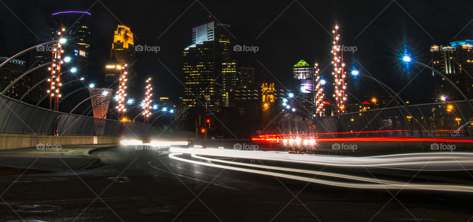 The downtown Minneapolis skyline stands above a freeway overpass as cars drive by on a February evening. Minneapolis, Minnesota.
