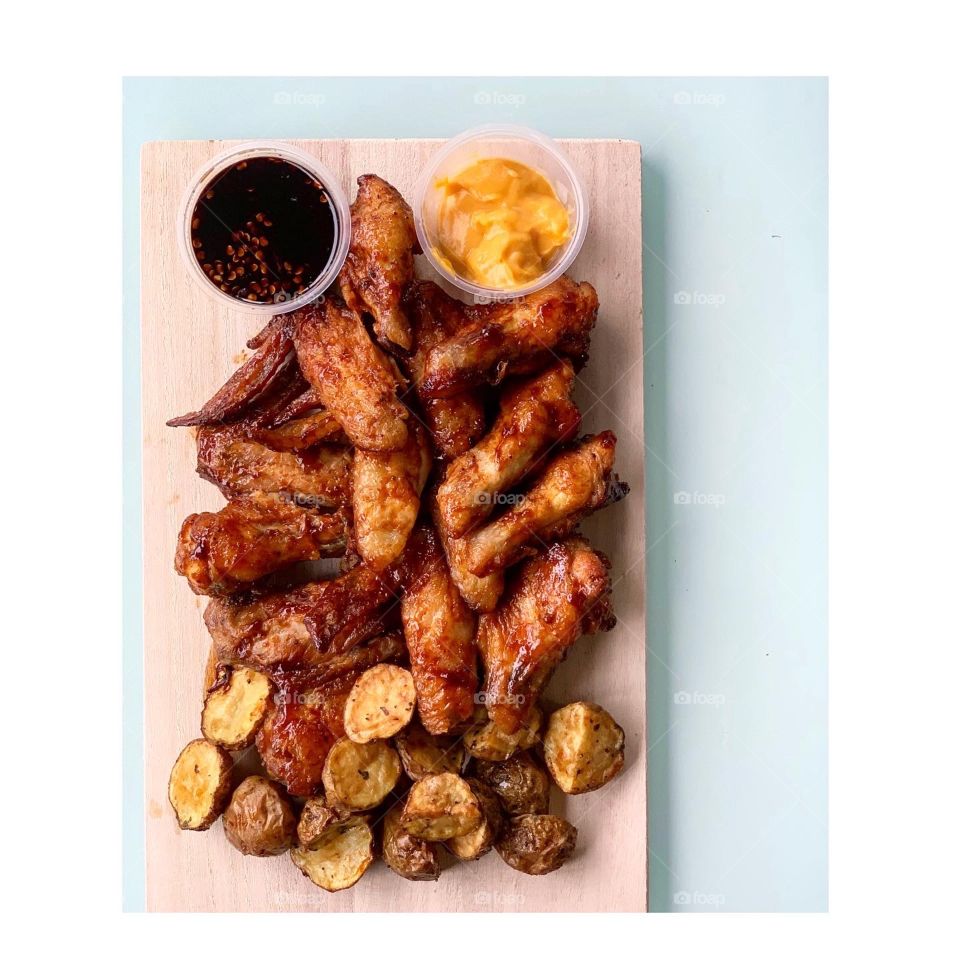 Barbecue chicken wings with nacho cheese sauce and mini potatoes flatlay