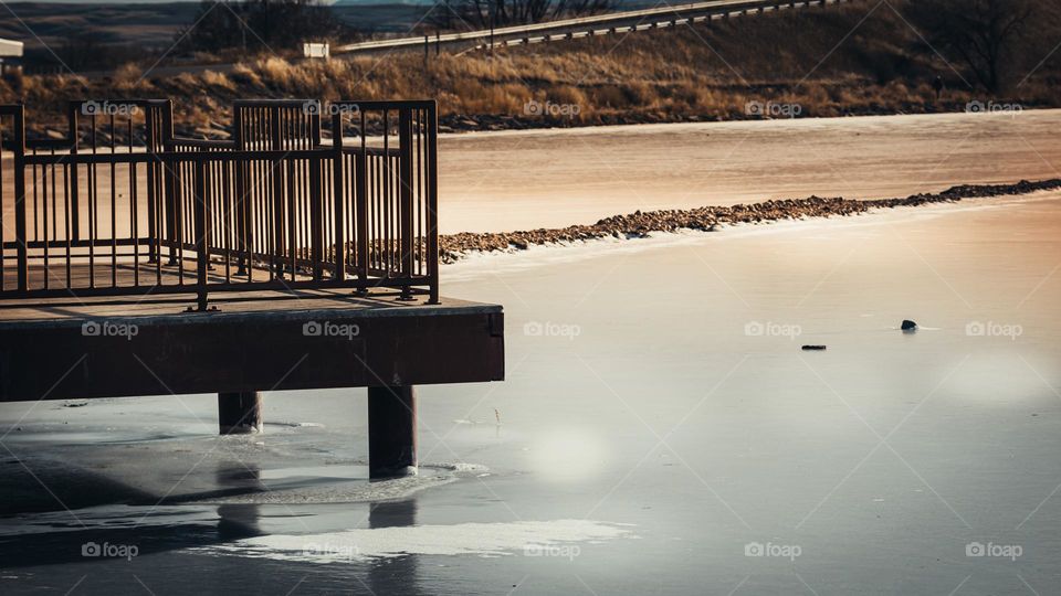 Concrete dock overlooking frozen pond.