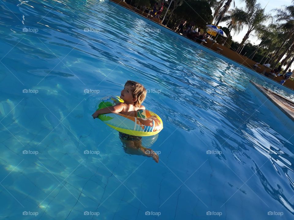 child playing with the float in the blue pool