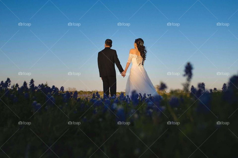 a newlyweds holding hand under sunset