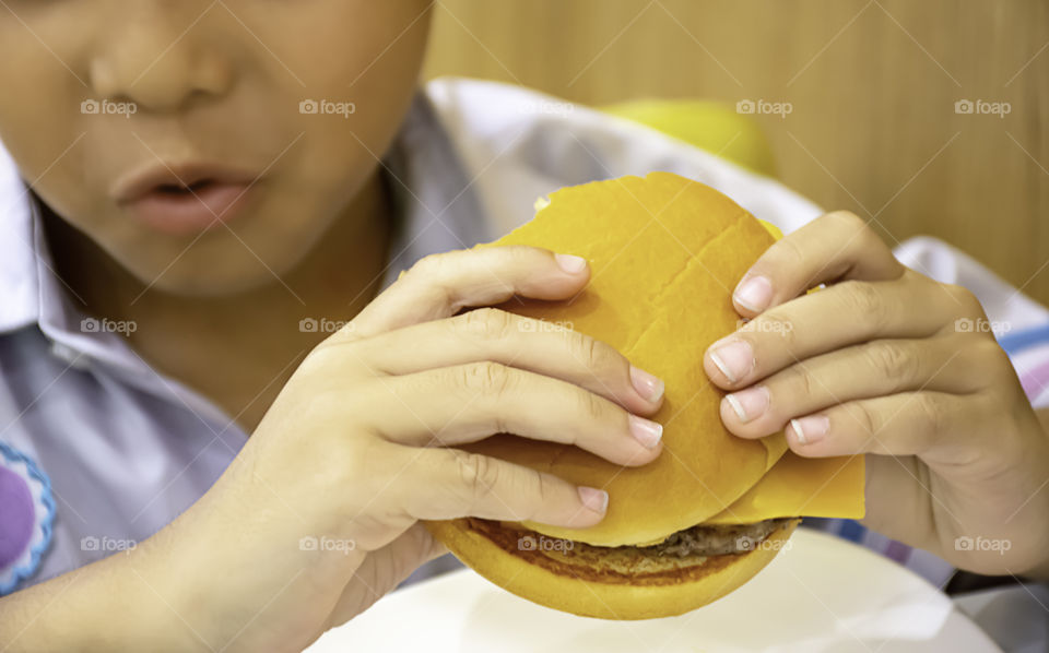 Hamburger fish and cheese in hand asia boy holding the eating.