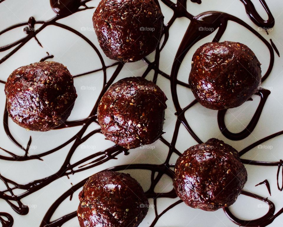 More Chocolate - Nut Butter Cocoa Bites on white plate with chocolate drizzle closeup flat lay