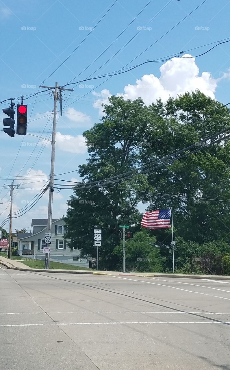 Empty town intersection, stop light lit. Street corner shows an American Flag blowing in the wind🇺🇸!
