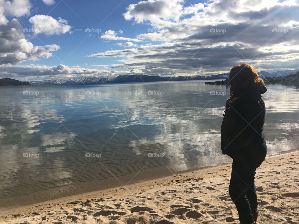 Woman enjoying the view of Lake Tahoe. Refection of clouds on the water and blue skies. 
