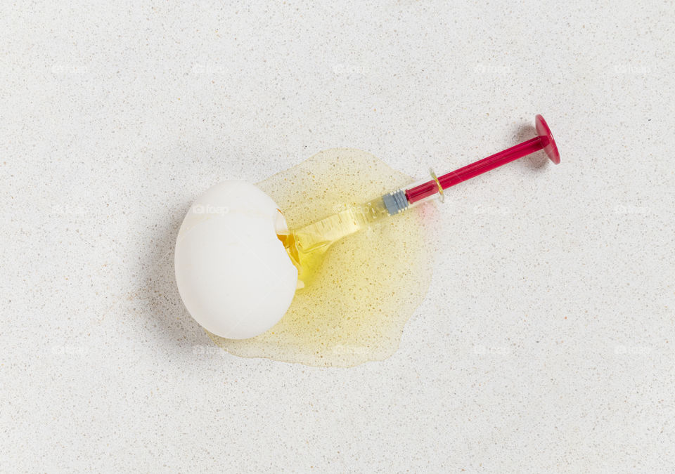 egg broken by red injection, representation of overdose, egg yolk, yellow