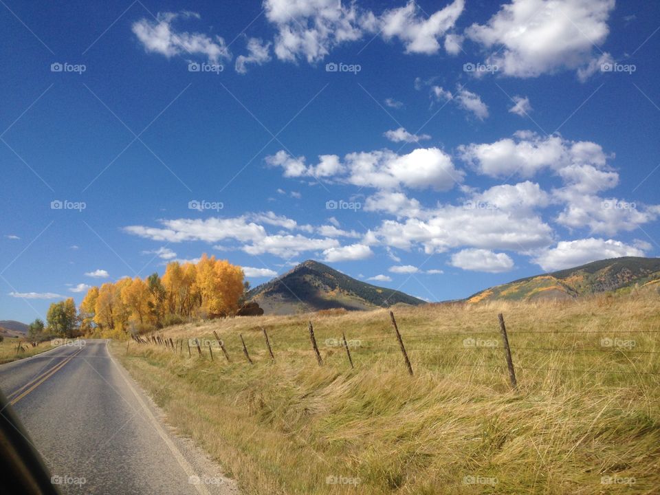 Autumnal Roads. Colorado clouds shadow mountainsides while travelers glide along. 