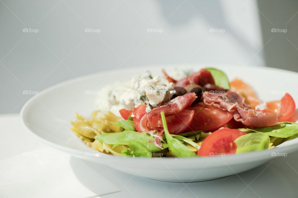 close-up of a young man eating a salad in a light kitchen