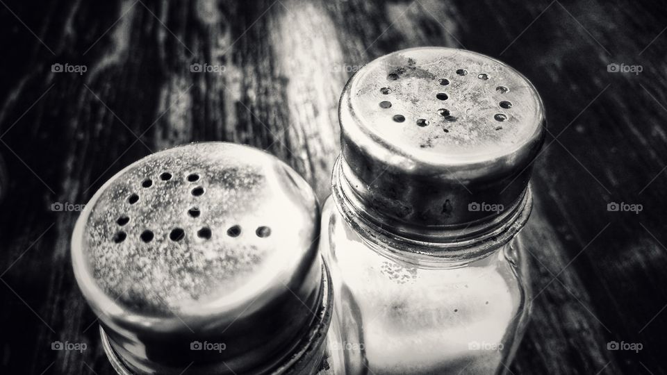 Pepper and salt shaker containers on a table. Monochrome version.