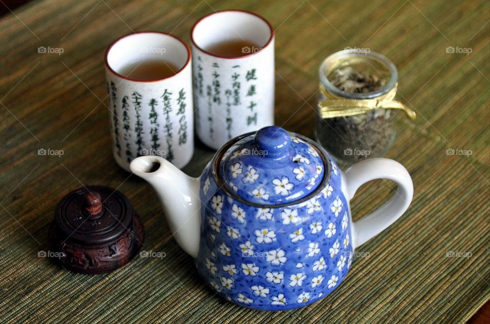 Elevated view of dried tea with cup of tea and teapot