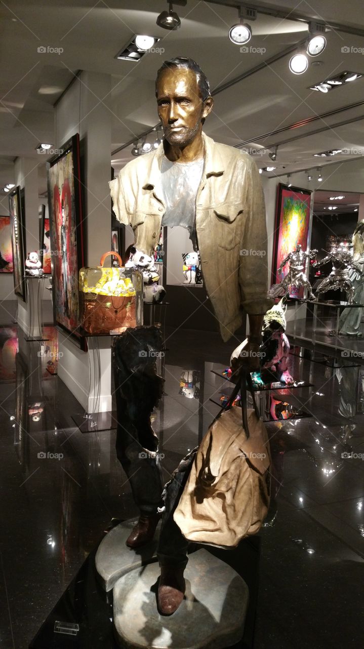 Metal sculpture man portrait carrying a bag with see through body, art