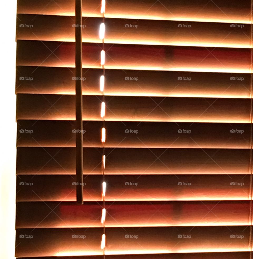 Morning light creeping through wooden blinds 
