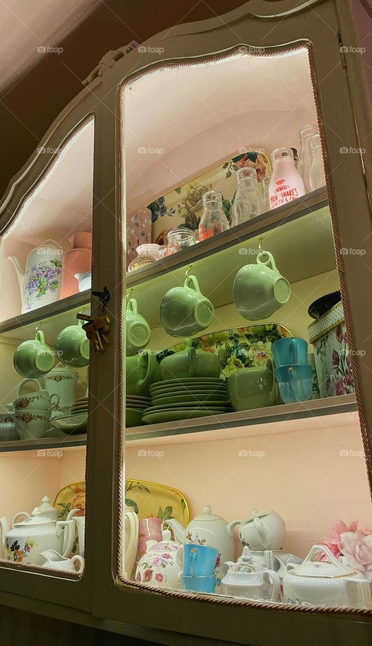 The cabinet has an elegant, old-fashioned design with a light cream color and a subtle rope detail along the edges.