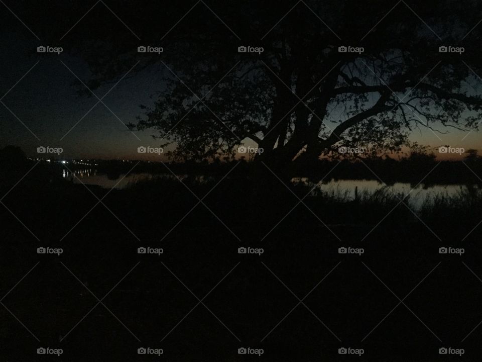 A picture of the river water reflecting the sky at sunset and city lights. 