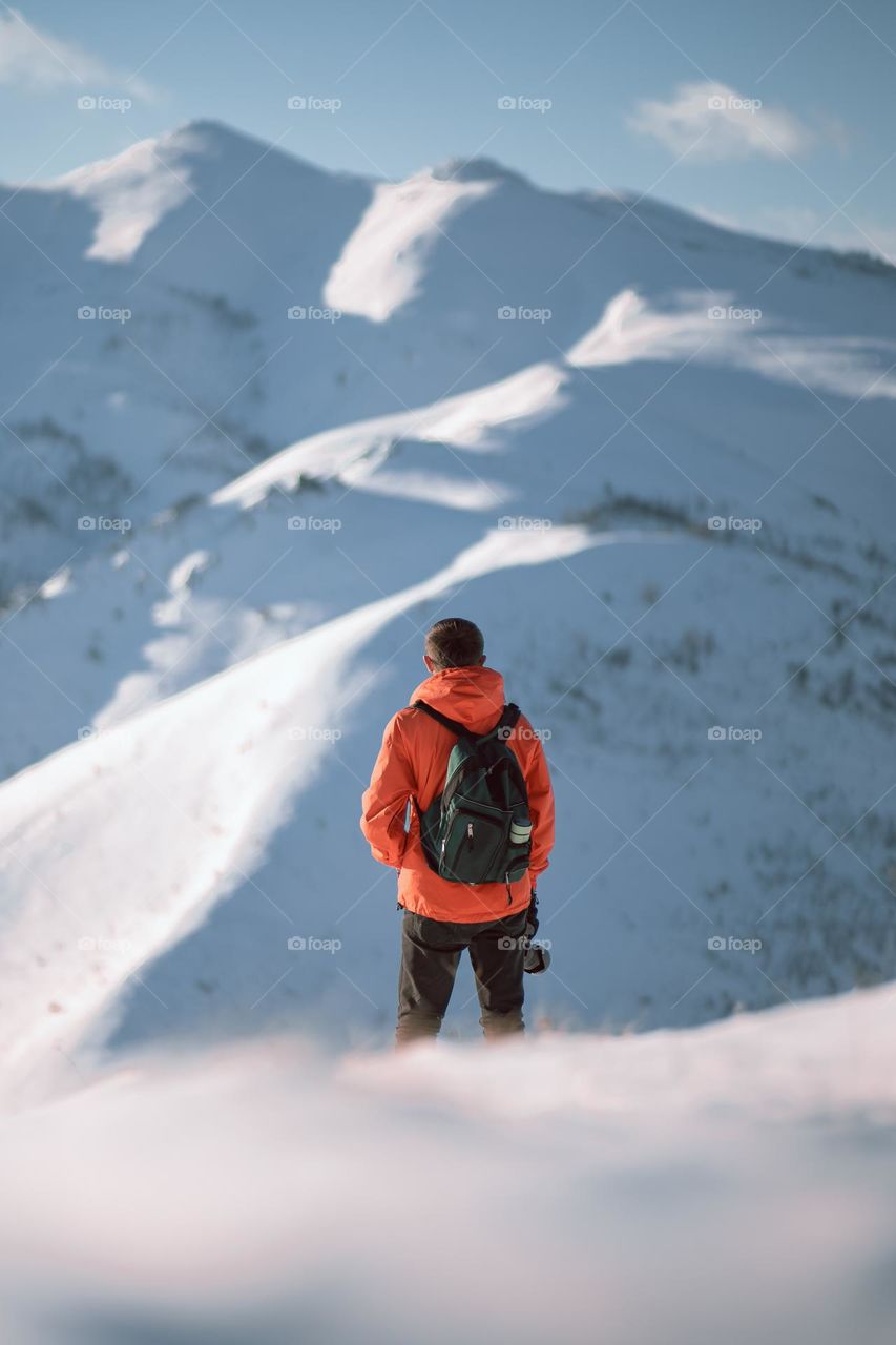 Male hiker standing on top of a snowy mountain enjoying the view.