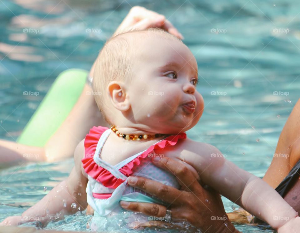 Parents carrying her daughter in swimming pool