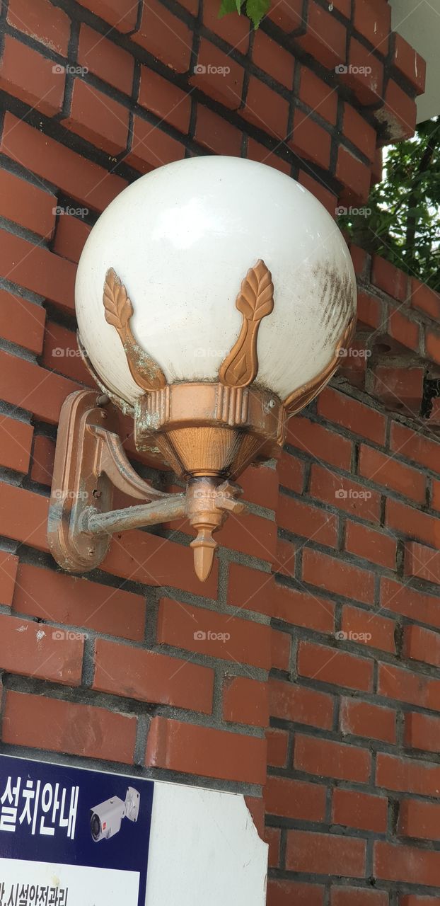old style light on wall with copper color with white glass globe