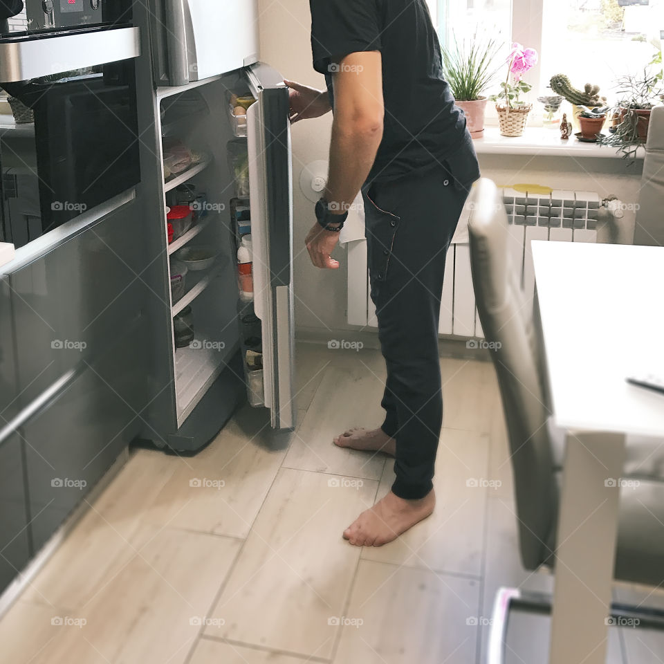 Young man searching for some food for breakfast in refrigerator in the kitchen at home 