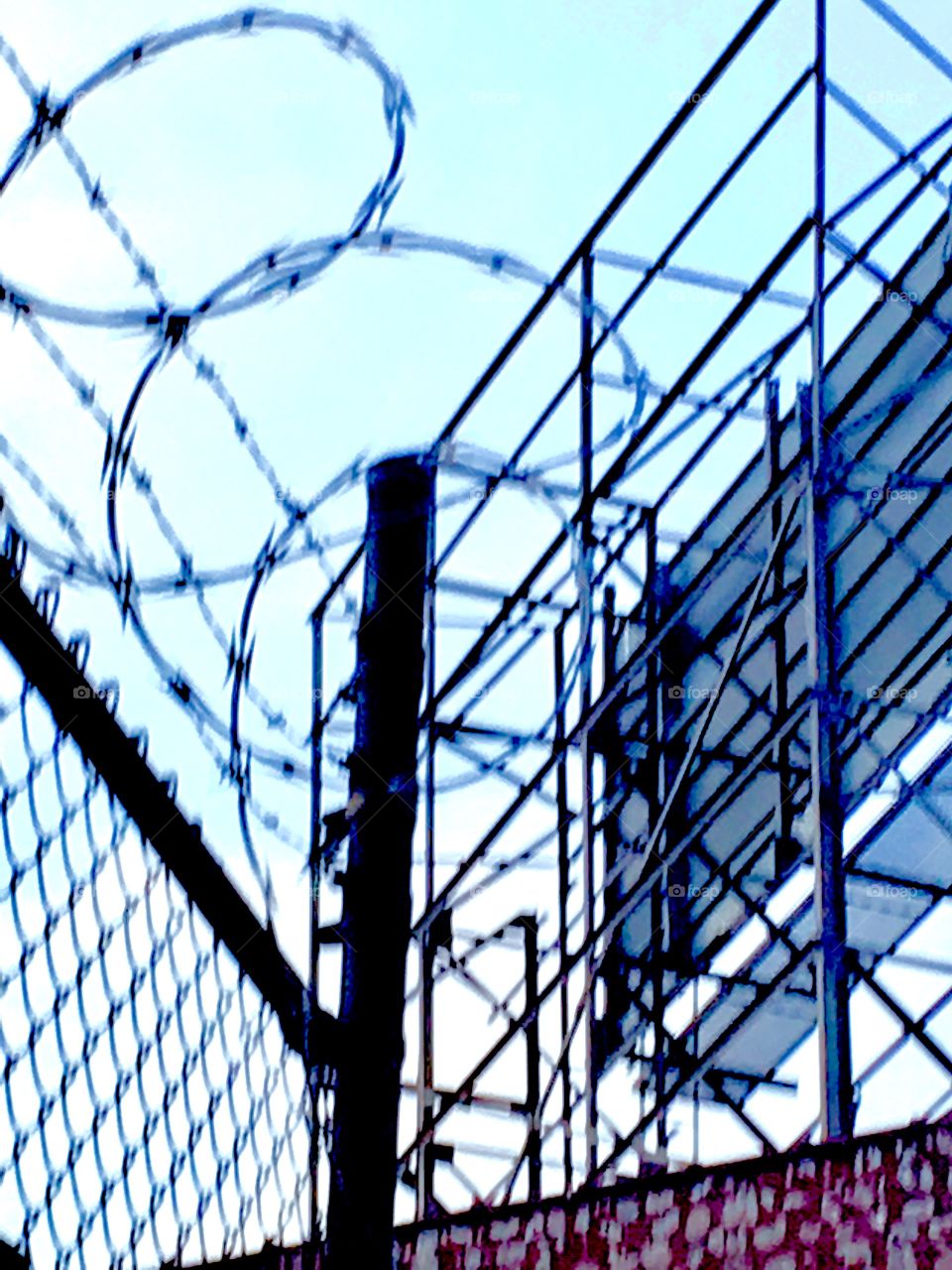 Barbed wire fence against the sky underneath the Pulaski Bridge in Long Island City, Queens, New York photographed in the Spring of 2019.