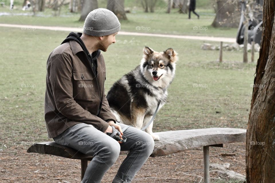 A man taking a break with his Finnish Lapphund dog 