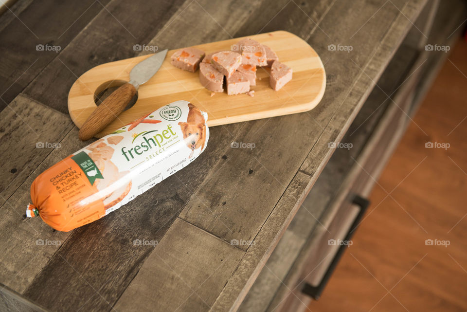 Roll of fresh dog food chopped up on a wooden counter