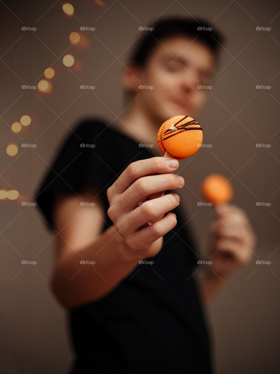Selective focus to orange macarons in hand of person blurred in background.