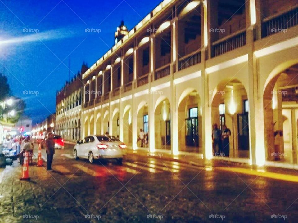 Night street in the city with traffic and walking pedestrians