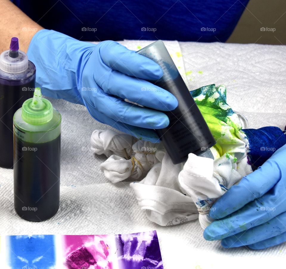 Person wearing Playtex disposable blue gloves while tie-dying a cotton t-shirt 
