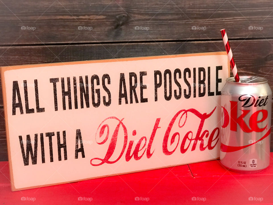 Diet Coke can with drinking straw. Wooden vintage sign and background. 