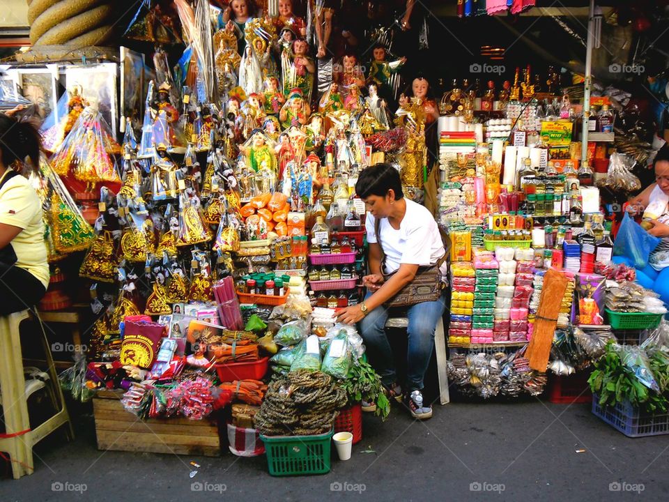 asian street vendor selling religious figurines outside of quiapo church in quiapo, manila, philippines in asia