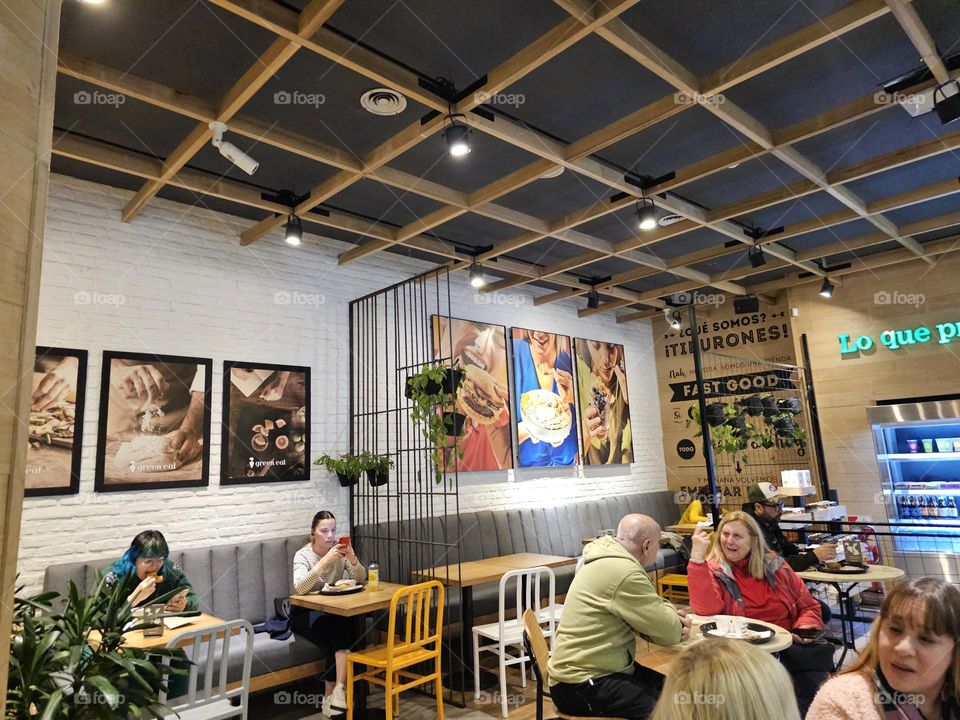 Coffee shop with nice lights, paintings on the wall, people seated enjoying it