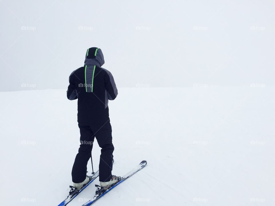 Skier in black ski costume surrounded by fog and snow